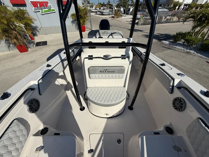 Slide: The Image of 2025 Sea Chaser 22 HFC boat interior with seating and console, parked outdoors. - 18