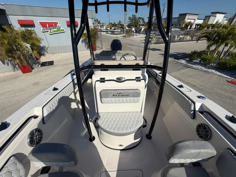 Slide: The Image of 2025 Sea Chaser 22 HFC boat interior with seating and console, parked outdoors. - 28