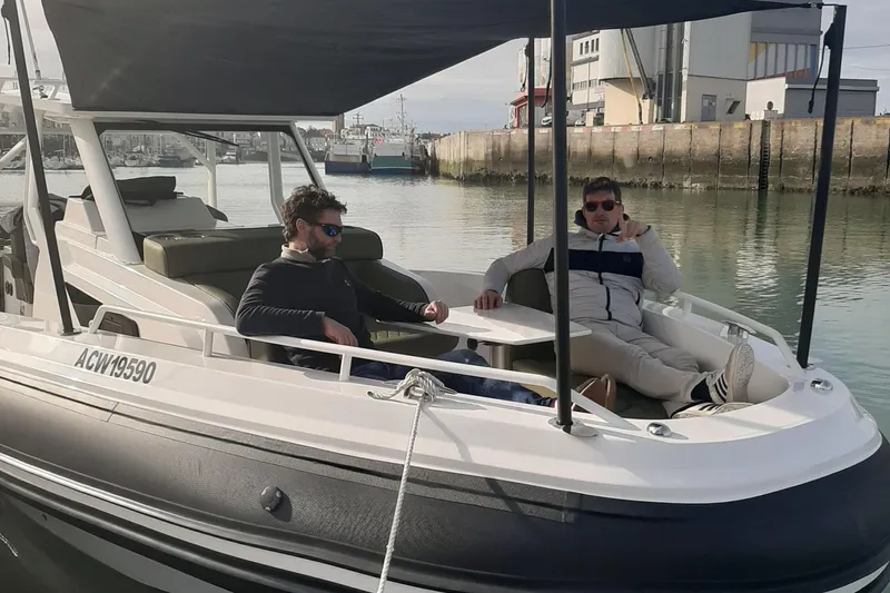 Slide: The Image of Two people relaxing on a 2025 Zodiac X10CC boat in a marina. - 18