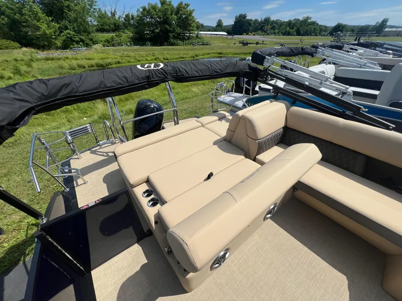 Slide: The Image of 2024 Harris Sunliner 230 pontoon boat with beige seating, outdoor setting. - 13
