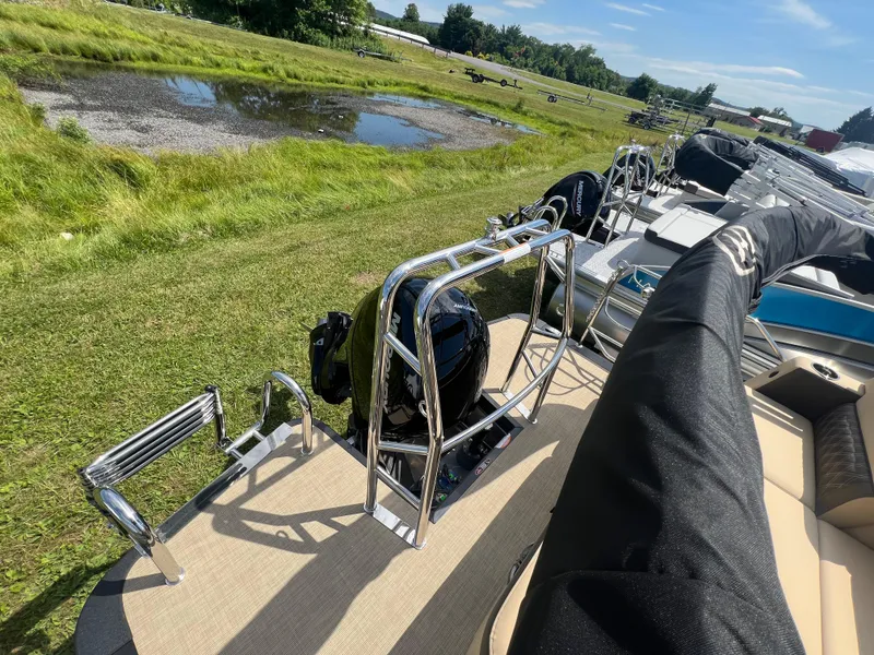 Slide: The Image of 2024 Harris Sunliner 230 pontoon boat on grassy field, sunny day. - 15