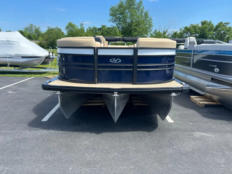 Slide: The Image of 2024 Harris Sunliner 230 pontoon boat in parking lot, blue and beige design. - 3