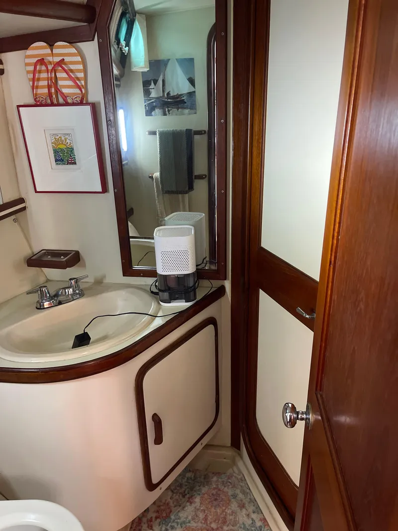 Slide: The Image of 1985 Gulfstar 45 Hirsch Center Cockpit bathroom with sink, mirror, and wooden cabinetry. - 29
