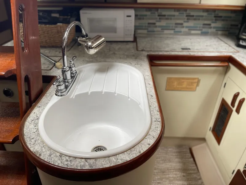 Slide: The Image of 1985 Gulfstar 45 Hirsch Center Cockpit kitchen with sink, microwave, and modern backsplash. - 35