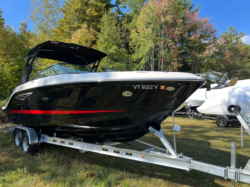 Slide: The Image of 2022 Sea Ray SLX 250 boat on trailer, parked outdoors with trees in background. - 22