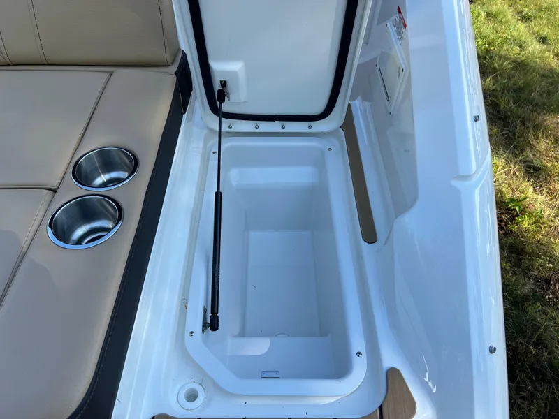 Slide: The Image of 2022 Sea Ray SLX 250 storage compartment with cup holders and beige seating. - 29