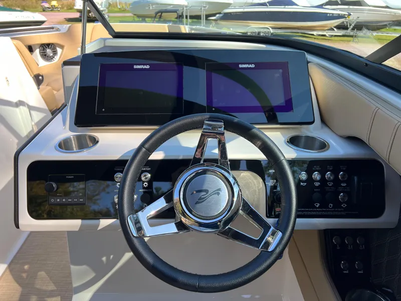Slide: The Image of 2022 Sea Ray SLX 250 dashboard with dual Simrad displays and sleek steering wheel. - 36