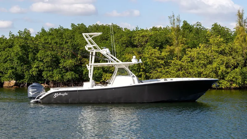 Slide: The Image of 2015 Yellowfin 39 Offshore boat on calm water near lush greenery. - 1