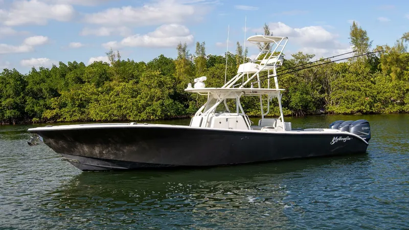 Slide: The Image of 2015 Yellowfin 39 Offshore boat on calm water, surrounded by lush greenery. - 2