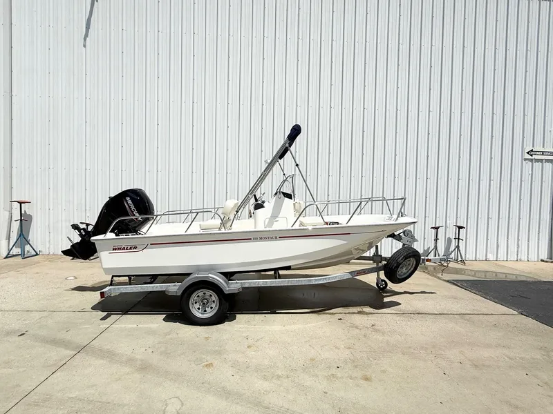 Slide: The Image of 2025 Boston Whaler 150 Montauk boat on trailer, parked outdoors. - 0