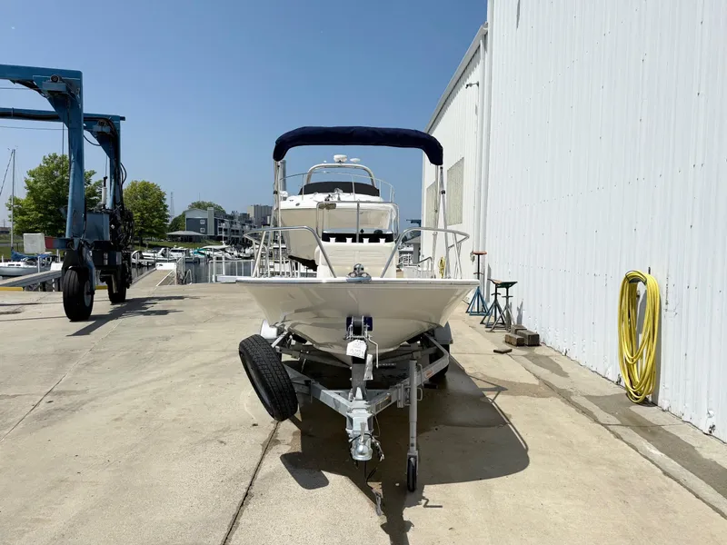 Slide: The Image of 2025 Boston Whaler 150 Montauk boat on trailer, dockside with marina background. - 2