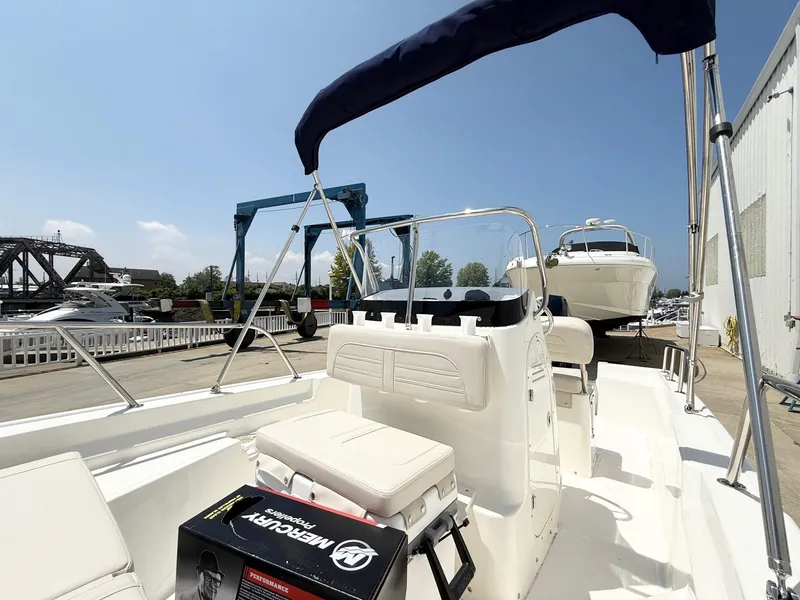 Slide: The Image of 2025 Boston Whaler 150 Montauk boat docked, featuring a Mercury engine box. - 6