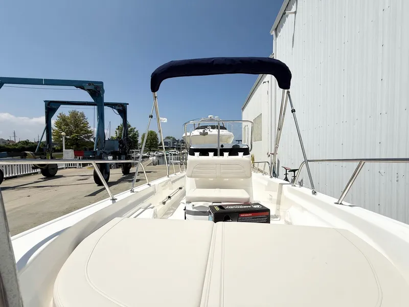 Slide: The Image of 2025 Boston Whaler 150 Montauk boat docked, featuring spacious seating and a blue canopy. - 7