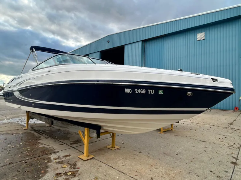 Slide: The Image of 2015 Rinker Captiva 276 BR boat on stands near a blue warehouse. - 1