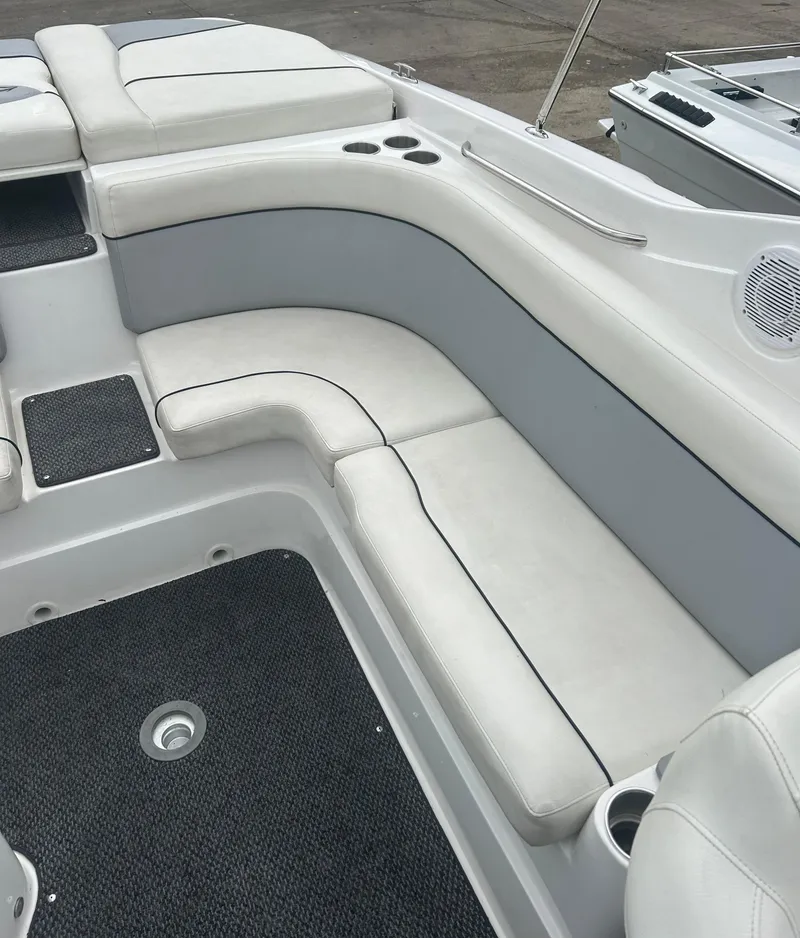 Slide: The Image of 2015 Rinker Captiva 276 BR boat interior with white cushioned seating and cup holders. - 19
