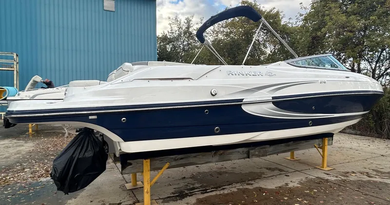 Slide: The Image of 2015 Rinker Captiva 276 BR boat on stands, blue and white design, outdoors. - 7