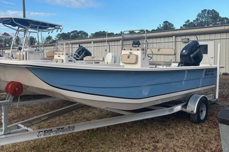 The Image of 2024 Carolina Skiff E21 DLX CC boat on trailer, light blue hull, outdoor display. - 1