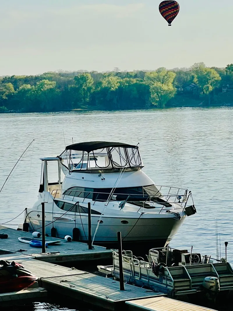 Slide: The Image of 2004 Meridian 459 Motoryacht with dog on deck, named "On The Rocks," docked on calm water. - 4