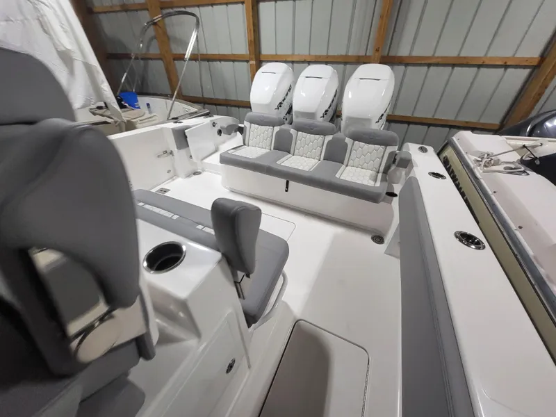 Slide: The Image of 2022 Fountain 38 SC boat interior with triple engines and seating in a storage facility. - 14