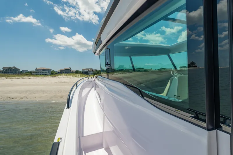 Slide: The Image of 2025 Axopar 45 XC Cross Cabin boat near sandy beach under blue sky. - 22