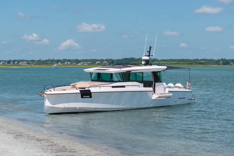 Slide: The Image of 2025 Axopar 45 XC Cross Cabin boat anchored on a serene shoreline. - 13