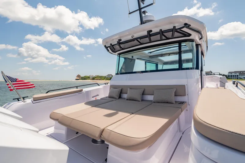 Slide: The Image of 2025 Axopar 45 XC Cross Cabin boat with sun deck and American flag on calm water. - 29
