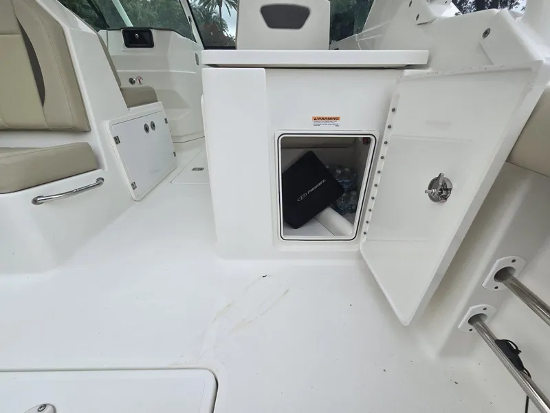 Slide: The Image of Open storage compartment on 2020 Pursuit 266 boat interior, featuring white seating and sleek design. - 12