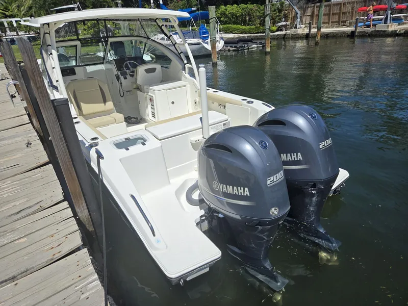 Slide: The Image of 2020 Pursuit 266 boat with dual Yamaha 200 engines docked by a wooden pier. - 3