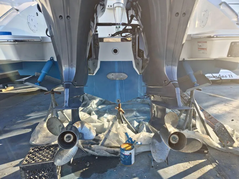 Slide: The Image of 2020 Pursuit 266 boat with dual outboard motors and propellers, docked for maintenance. - 7