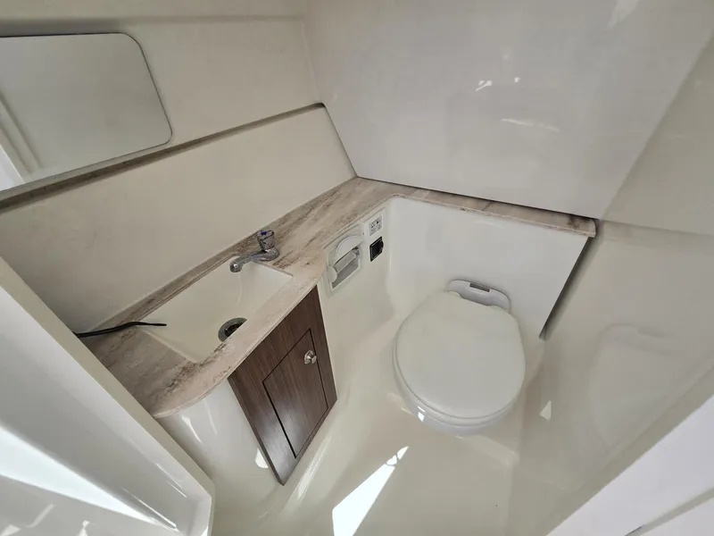 Slide: The Image of 2020 Pursuit 266 boat bathroom with sink, toilet, and mirror. - 9