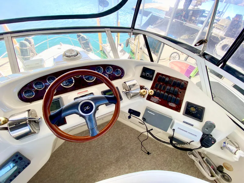 Slide: The Image of 2001 Sea Ray 380 Aft Cabin helm with wood-accented steering wheel and control panel. - 10