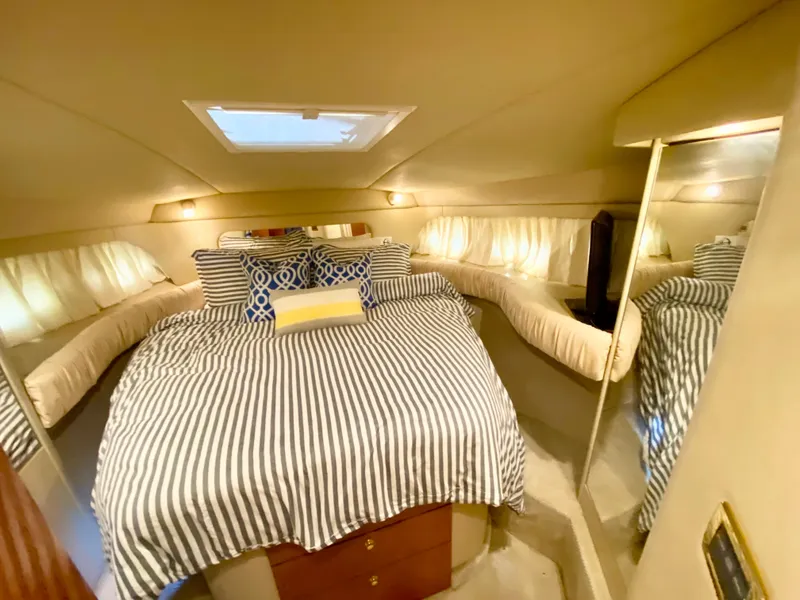 Slide: The Image of Luxurious 2001 Sea Ray 380 Aft Cabin bedroom with striped bedding and elegant decor. - 24
