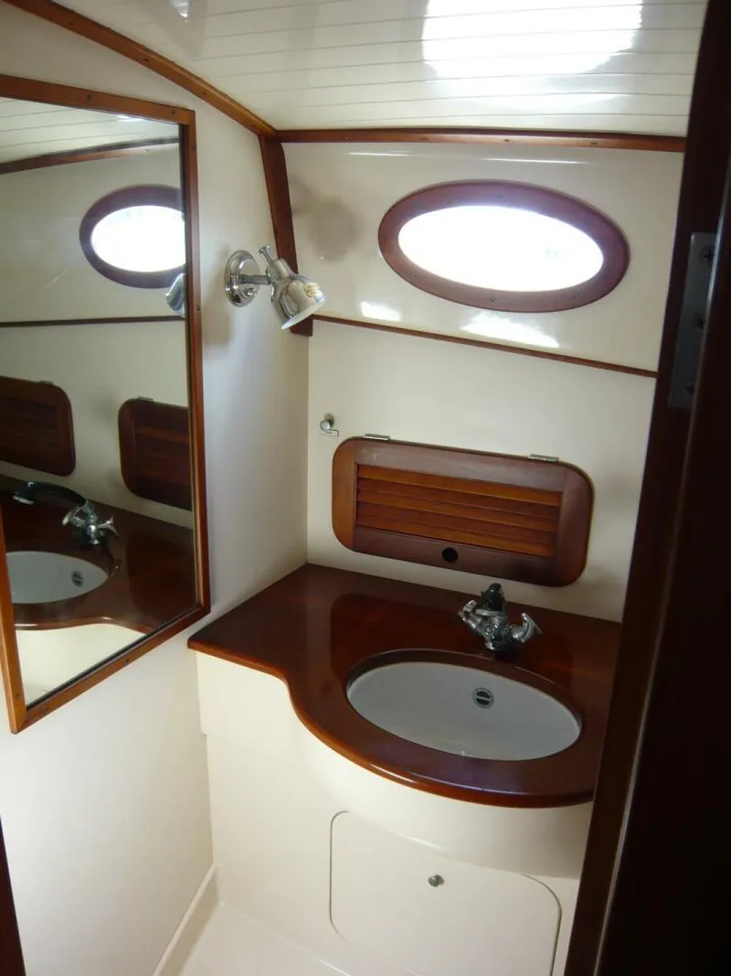Slide: The Image of Hinckley 36 Classic 1998 yacht bathroom with wooden accents and oval window. - 21