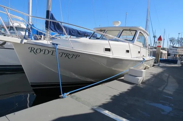 The Image of 2000 Mainship Pilot 34 docked, named "Rode Trip," with clear blue sky background. - 0