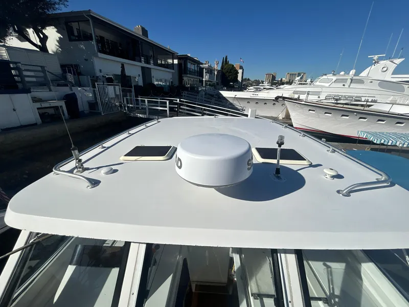 Slide: The Image of 2000 Mainship Pilot 34 boat docked at marina, showcasing roof and nearby vessels. - 13