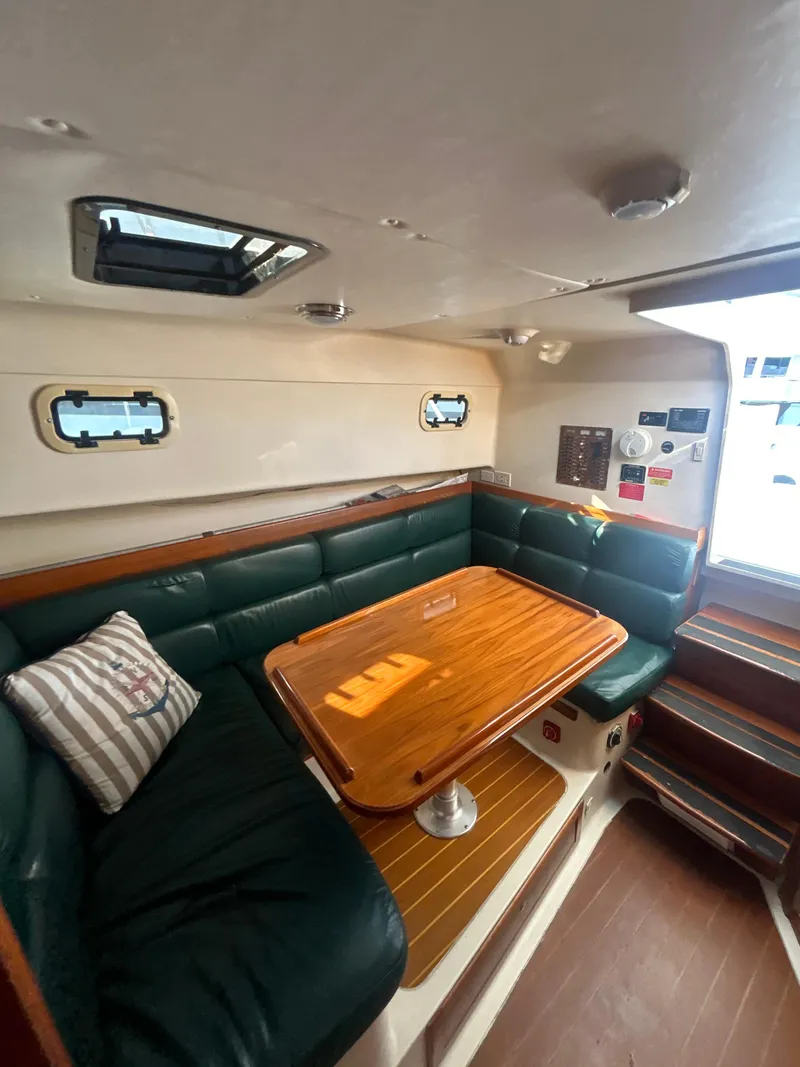 Slide: The Image of Interior of 2000 Mainship Pilot 34 with green seating and wooden table. - 15