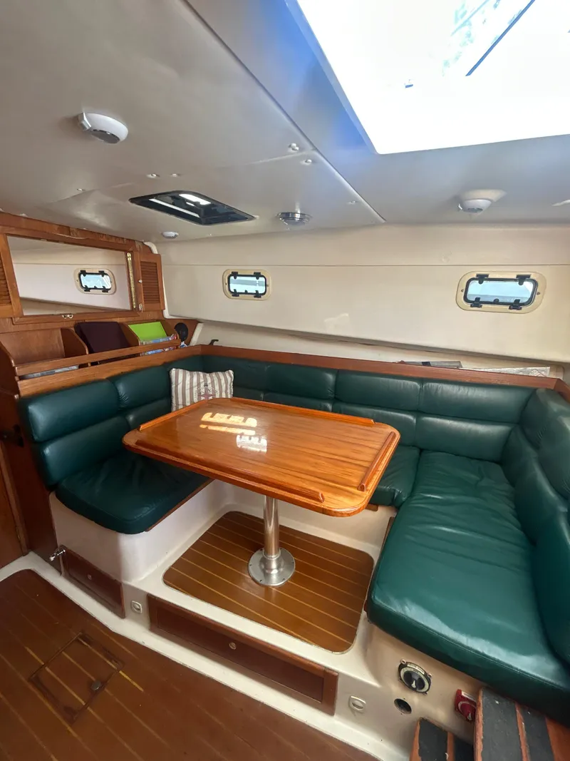 Slide: The Image of 2000 Mainship Pilot 34 interior with green leather seating and wooden table. - 18