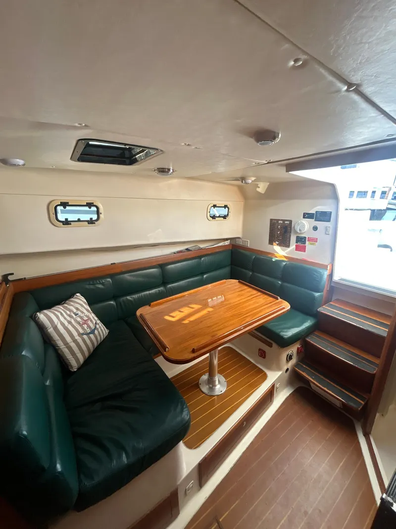 Slide: The Image of 2000 Mainship Pilot 34 interior with green seating and wooden table. - 19