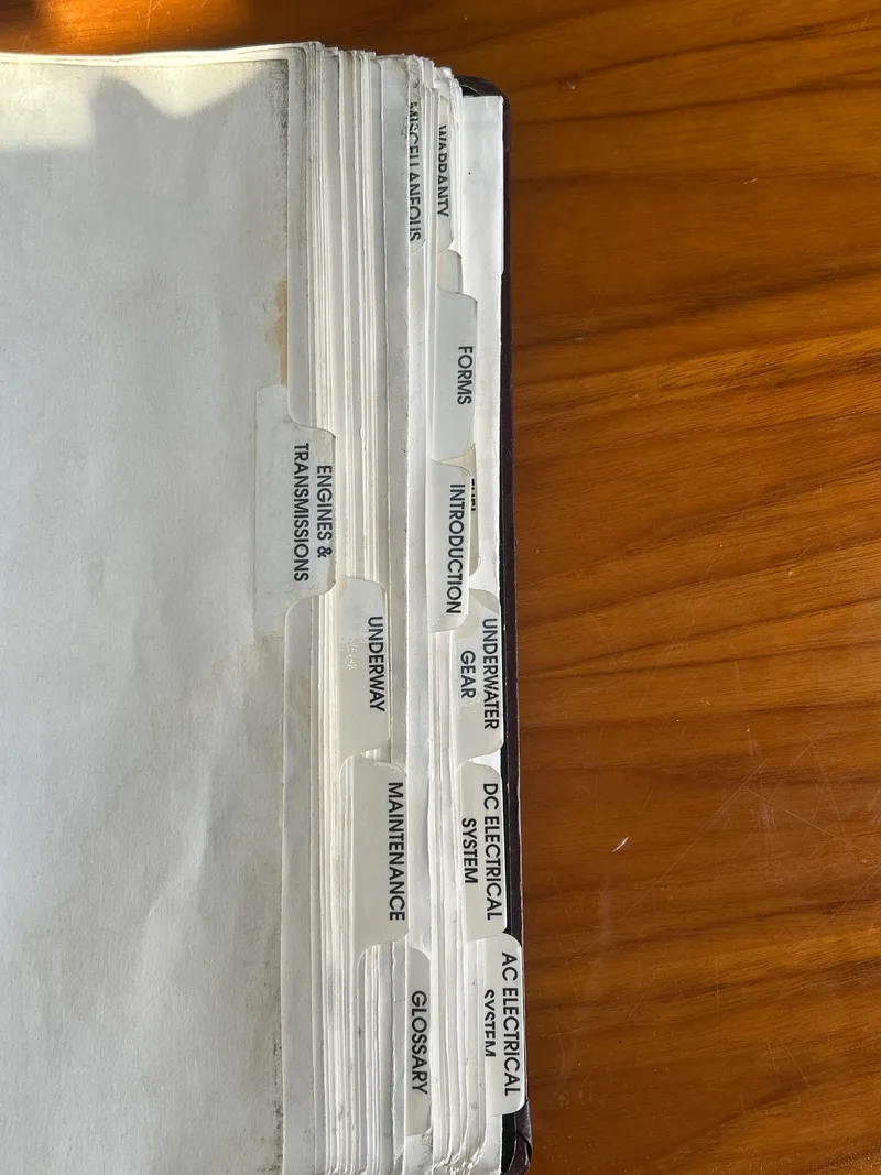 Slide: The Image of Mainship Pilot 34 2000 manual with labeled tabs on a wooden surface. - 21