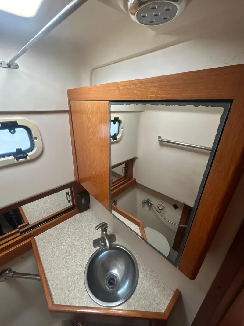 Slide: The Image of 2000 Mainship Pilot 34 bathroom with sink, mirror, and porthole window. - 22