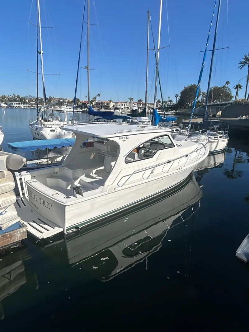 Slide: The Image of 2000 Mainship Pilot 34 docked in a marina, surrounded by sailboats under a clear blue sky. - 28