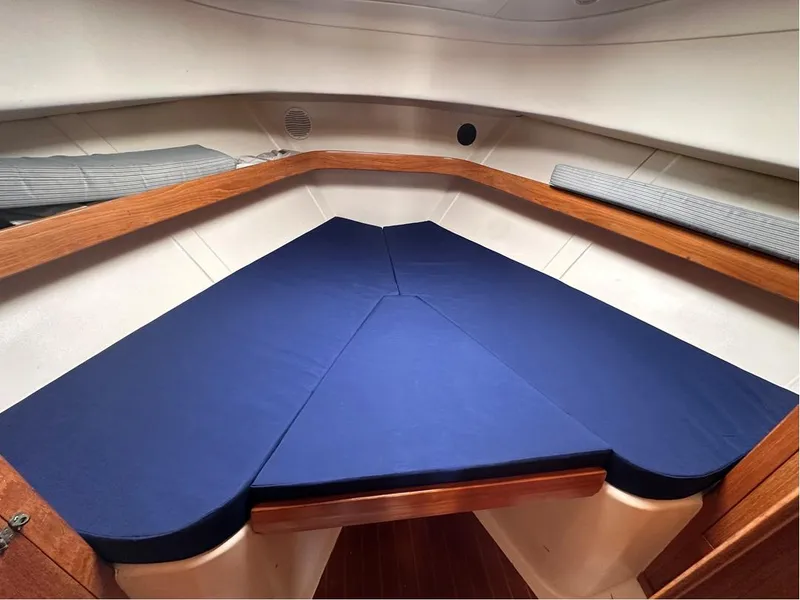 Slide: The Image of 2000 Mainship Pilot 34 interior cabin with blue cushions and wooden trim. - 34