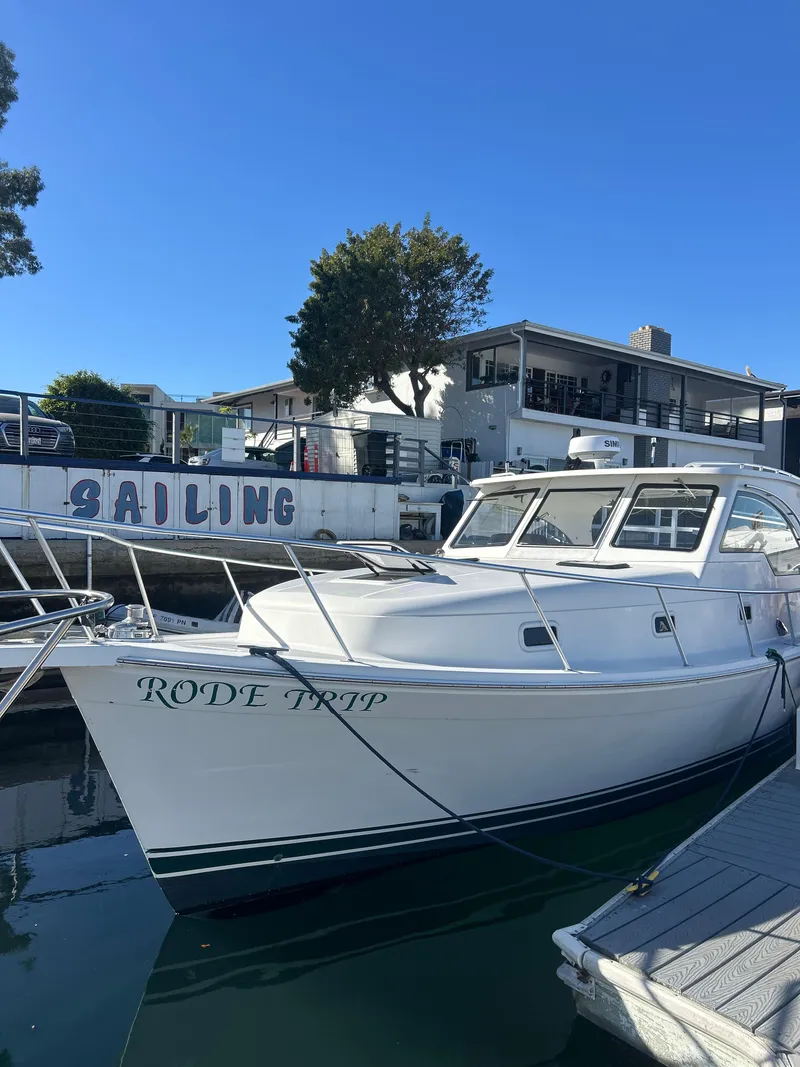 Slide: The Image of 2000 Mainship Pilot 34 docked at marina, clear sky, "Sailing" sign in background. - 4