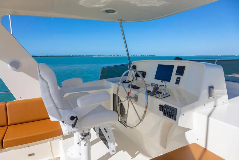 Slide: The Image of 2021 North Pacific 49 Euro Pilothouse helm with ocean view, featuring modern controls and seating. - 30