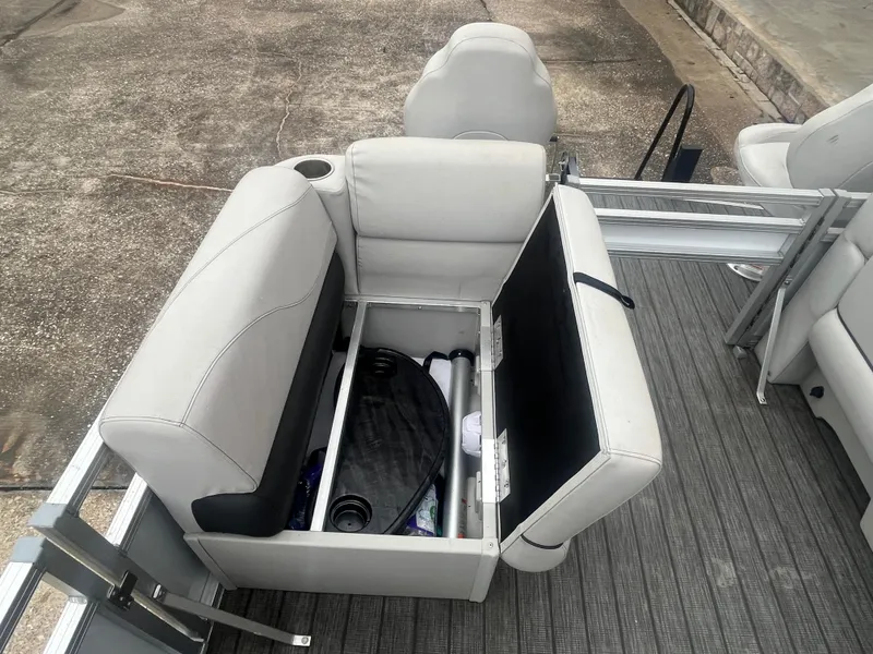 Slide: The Image of 2022 Avalon 2080 VENTURE FNC boat seat storage compartment open, revealing interior items. - 17
