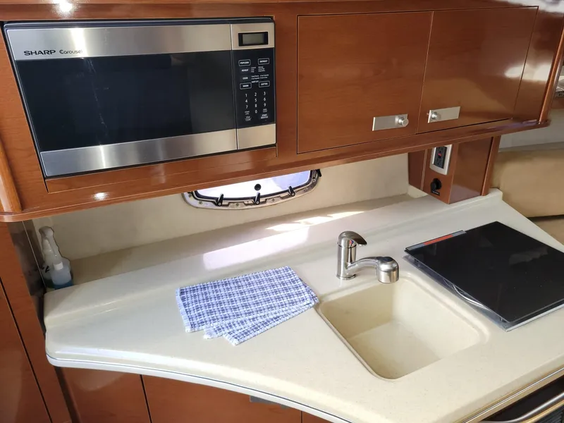 Slide: The Image of 2010 Sea Ray 280 Sundancer kitchen with microwave, sink, and countertop. - 25