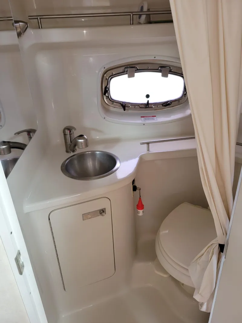 Slide: The Image of 2010 Sea Ray 280 Sundancer bathroom with sink, toilet, and porthole window. - 31