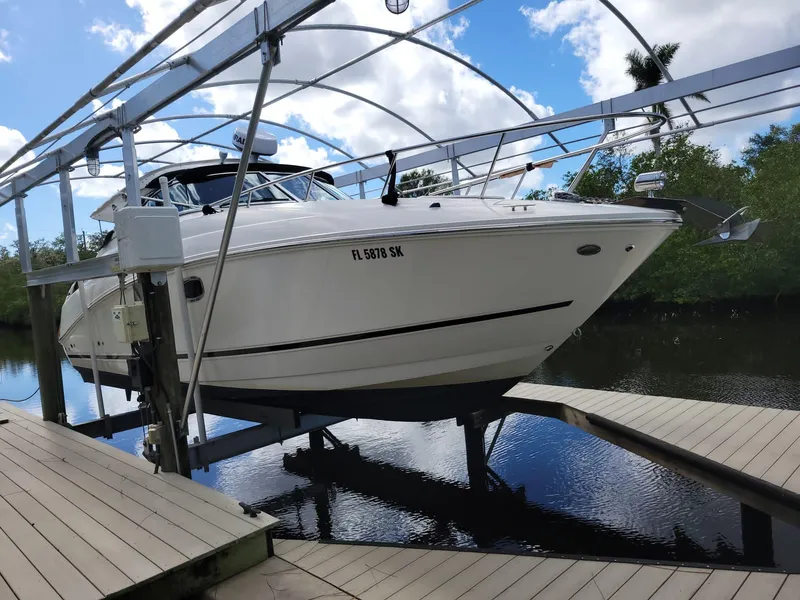 Slide: The Image of 2010 Sea Ray 280 Sundancer on boat lift, docked by lush greenery. - 4