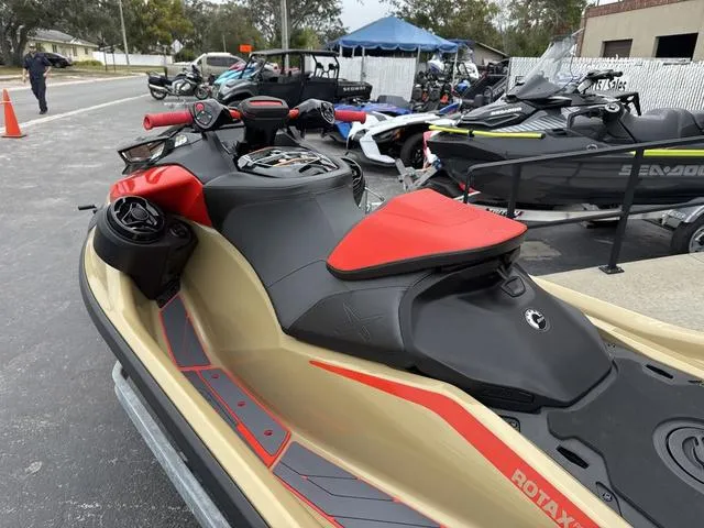 Slide: The Image of 2025 Sea-Doo Waverunner PWC RXP X 325, red and gold, parked outdoors. - 5