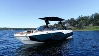 Slide: The Image of 2024 Malibu M242 boat on a lake with trees in the background. - 4